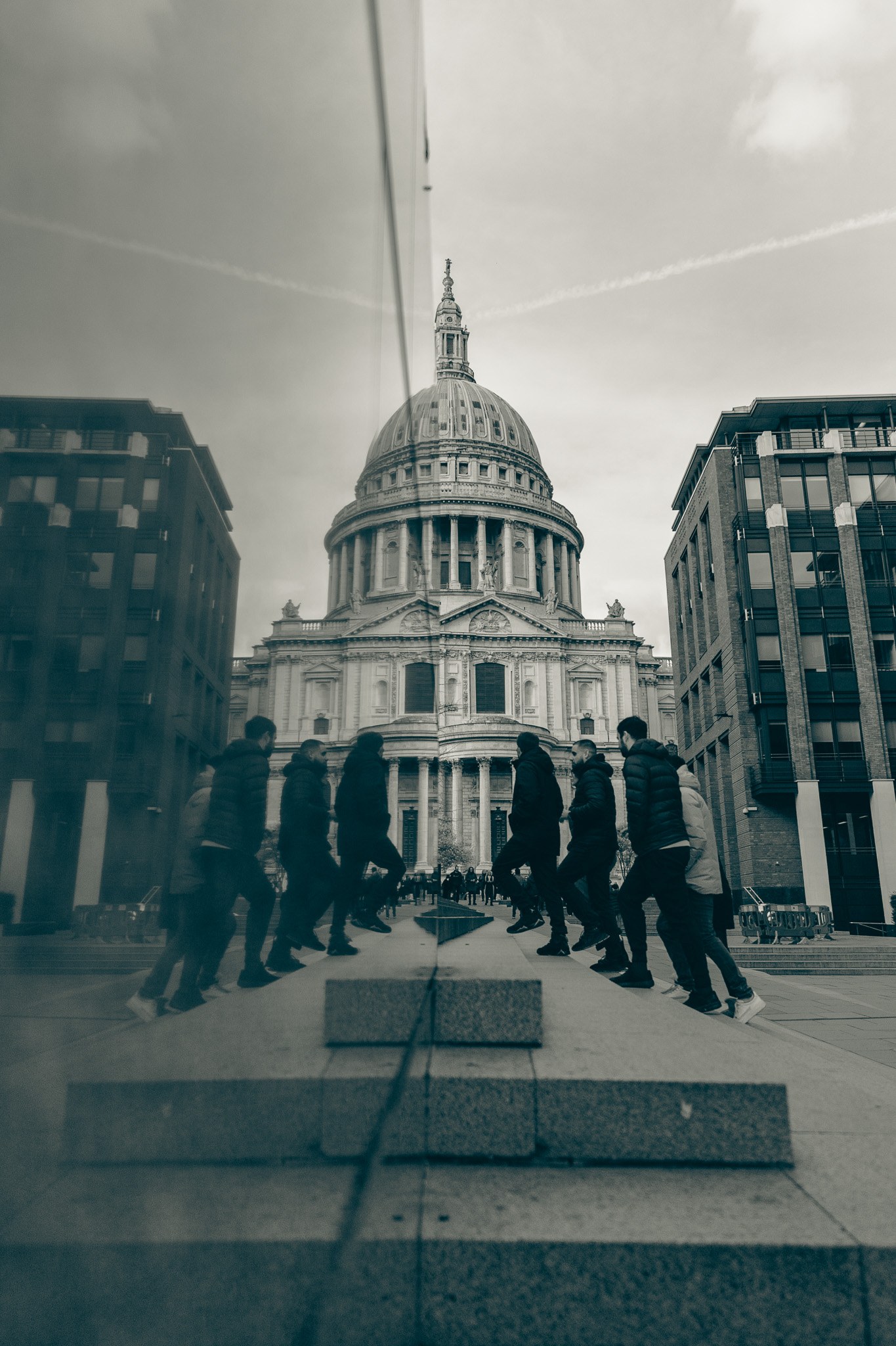 St Paul’s Cathedral seen beside a reflective surface on a city walkway.